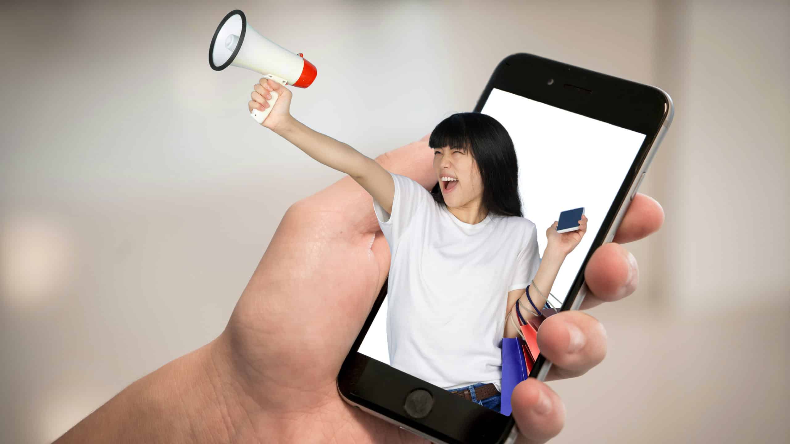 A person holds a phone with an influencer holding a microphone leaping out of the phone representing using sponsored content.