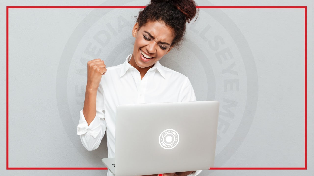 A woman on a laptop pumps her fist as Bullseye helps her small business with SEO